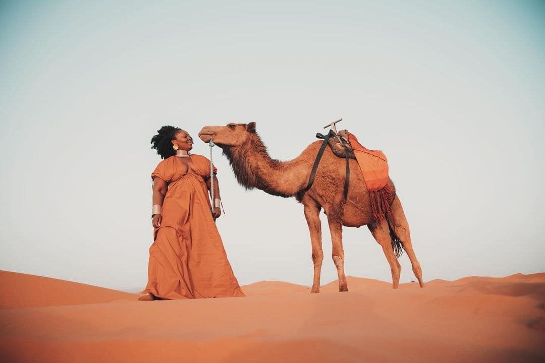A traveller with her camel in the Sahara dunes